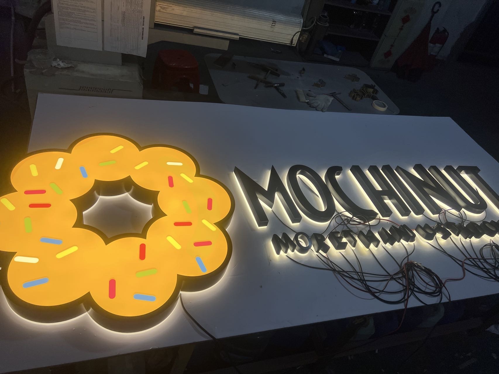 Custom illuminated logo and black halo-lit letters undergoing factory lighting test
