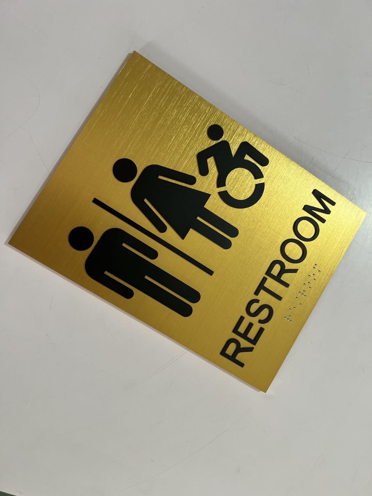 Landscape brushed gold restroom sign with accessible male and female pictograms and Braille