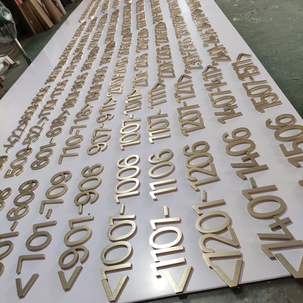 Brass hotel wayfinding numbers with controlled finish and typography