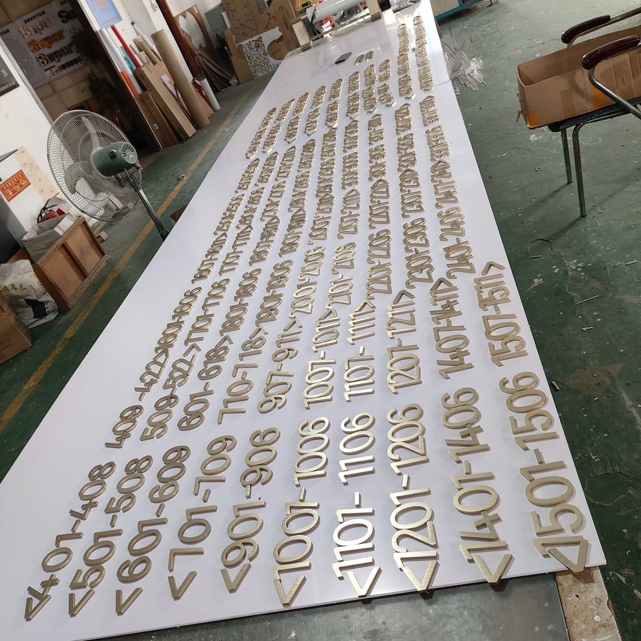Large batch of brass hotel room directional numbers arranged for quality inspection