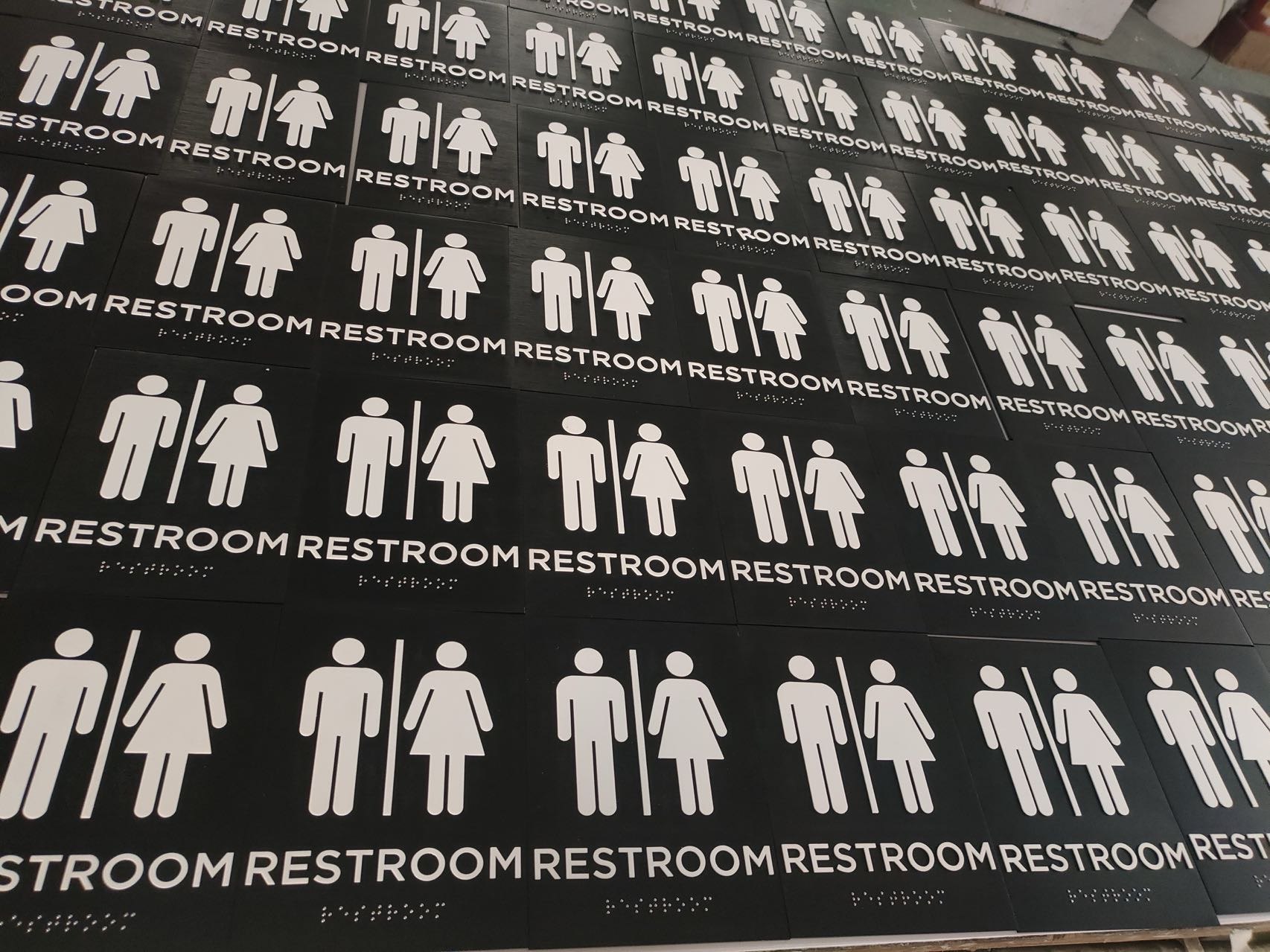 Large production run of black hotel restroom signs arranged in rows
